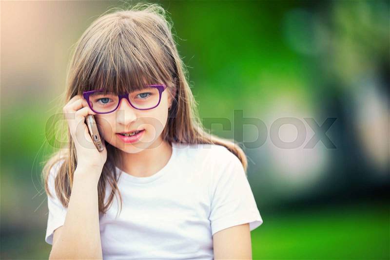 Cute little girl in the park on a sunny day with ice cream and mobile phone, stock photo
