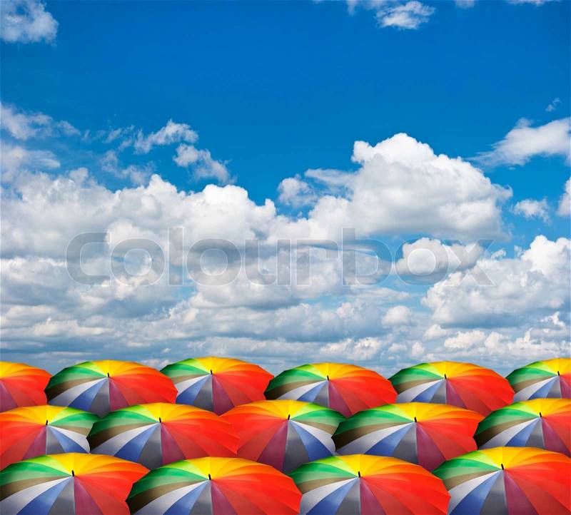 Rainbow umbrellas on beautiful cloudy sky, stock photo