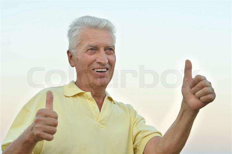 Mature man enjoying fresh air on nature with thumbs up, stock photo