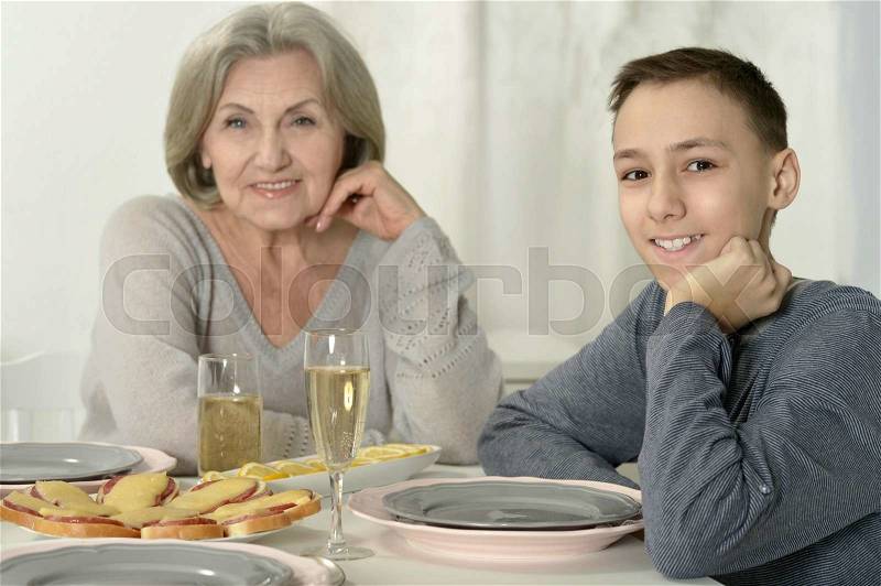 Portrait of cute grandmother with kid at dinner, stock photo