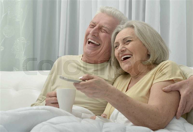 Portrait of a happy senior couple resting in bed, stock photo