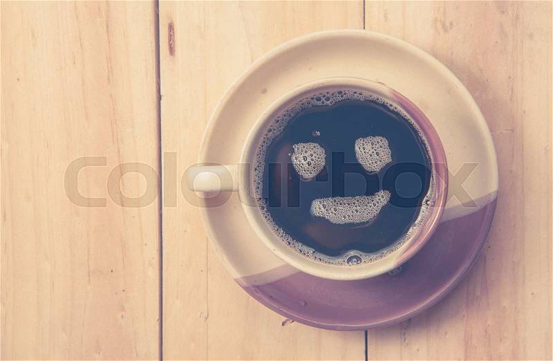 Espresso Cup with smiley face on wooden table, overhead view ,vintage color toned image, stock photo
