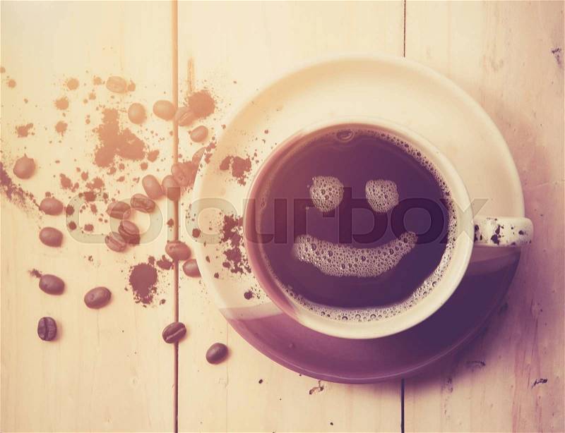Espresso Cup with smiley face on wooden table, overhead view ,vintage color toned image, stock photo