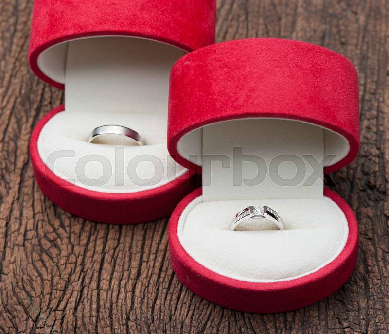 Diamond ring in red velvet box on wood, stock photo