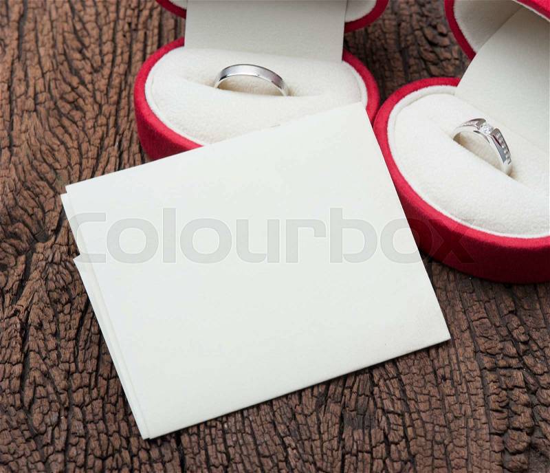 Diamond ring in red velvet box with blank notepaper on wood, stock photo