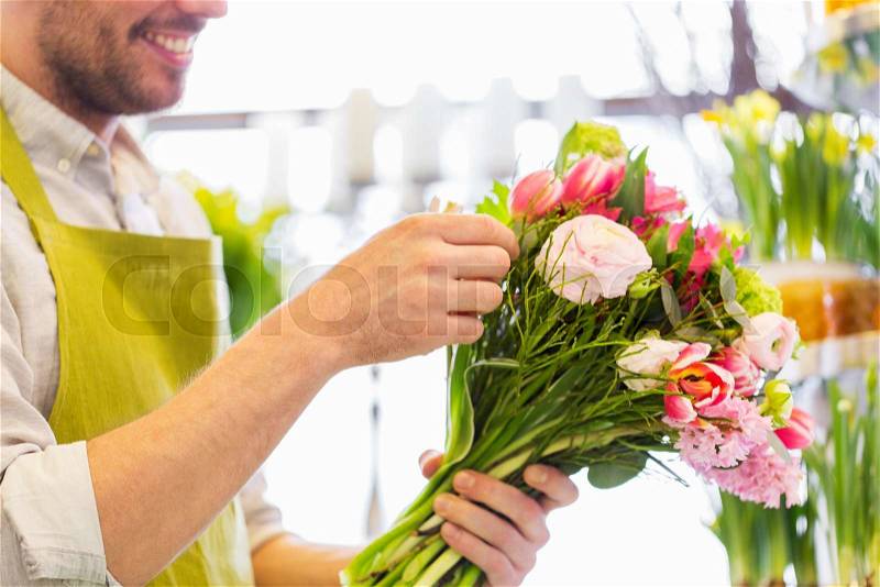 People, business, sale and floristry concept - close up of happy smiling florist man making bunch at flower shop, stock photo