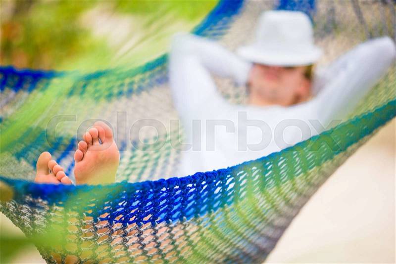 Lazy time. Man in hat in a hammock on a summer day, stock photo