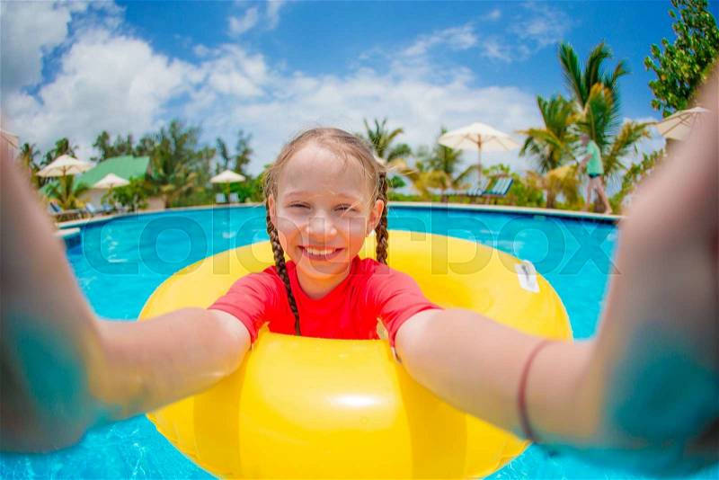 Little happy girl making selfie at inflatable rubber ring in swimming pool, stock photo