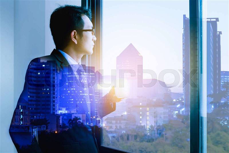Double exposure of businessman drinking hot coffee by the window with cityscape. , stock photo