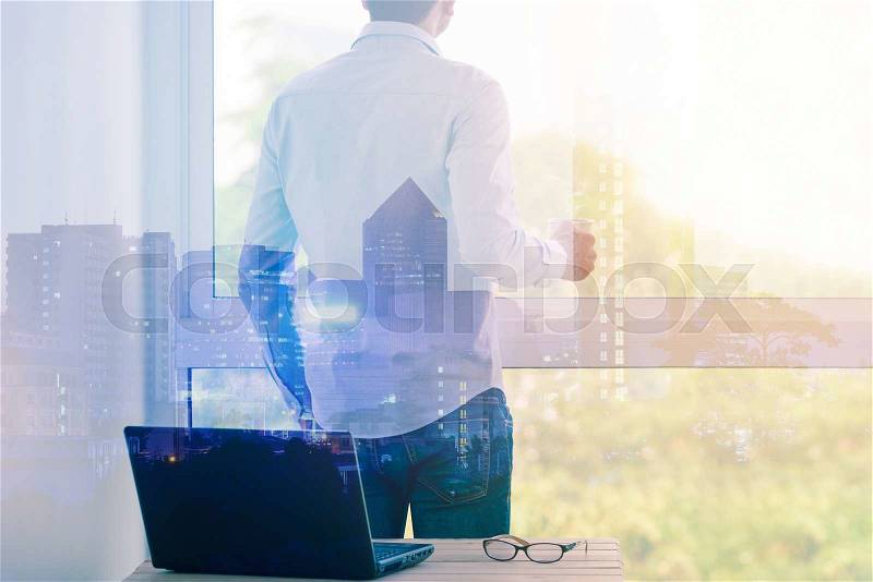 Double exposure of businessman relaxing with hot coffee by the window on cityscape, stock photo