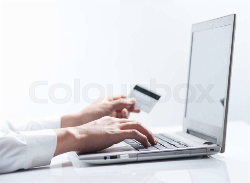 Man with credit card using a laptop computer for internet shopping, stock photo