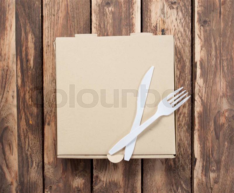 Blank pizza box with Plastic knife and fork on wood background, stock photo