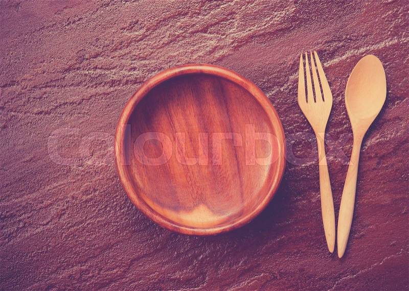 Empty bowl with fork and spoon on stone background,,vintage color toned image, stock photo