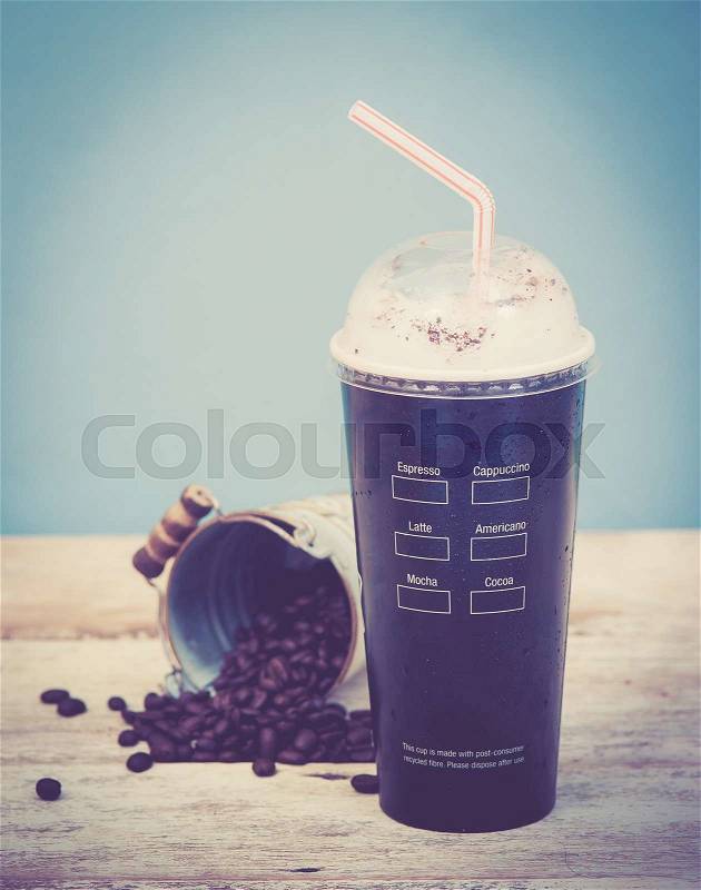 Iced coffee with coffee beans on wood vintage background,Selective focus on paper cup,vintage tone style, stock photo