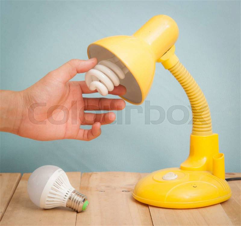 Hand changing a regular light bulb for LED,vintage background, stock photo