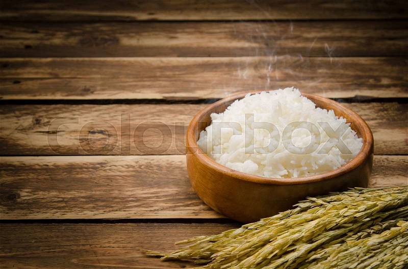 Cooked rice and paddy rice on wood, stock photo