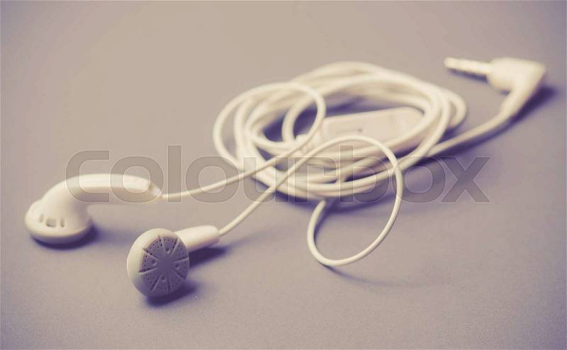 White earphones on the gray background,vintage color toned image, stock photo