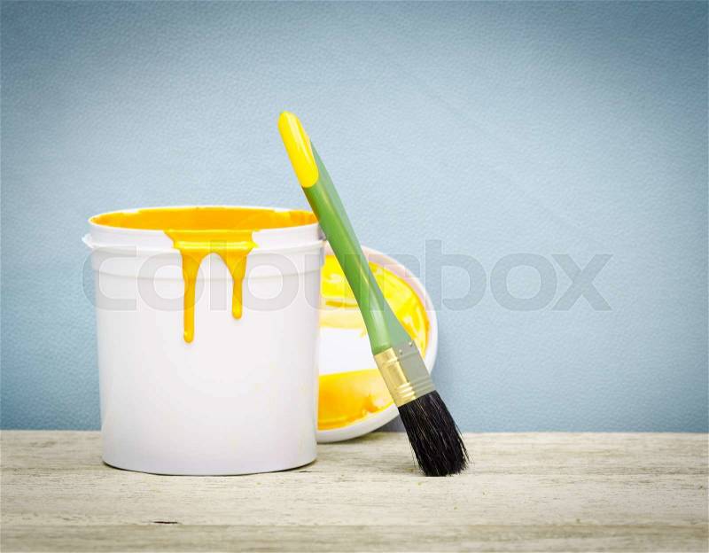 White plastic bucket with yellow color paint and brush on wood,vintage background, stock photo