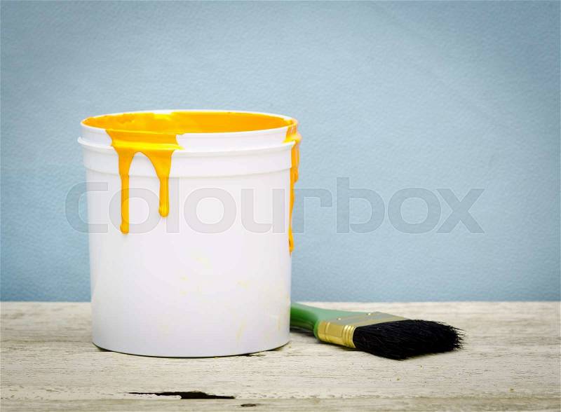 White plastic bucket with yellow color paint and brush on wood,vintage background, stock photo