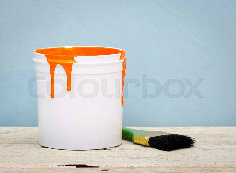 White plastic bucket with orange color paint and brush on wood,vintage background, stock photo