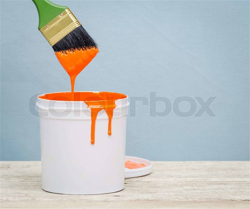 White plastic bucket with orange color paint and brush on wood,vintage background, stock photo
