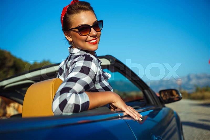 Beautiful pin up woman sitting in cabriolet, enjoying trip on luxury modern car with open roof, fashionable lifestyle concept, stock photo