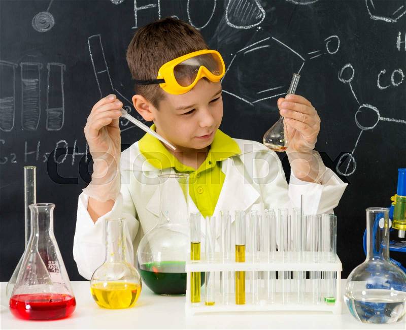 Schoolboy gown and gloves watching chemical experiment in tube in chemistry lab, stock photo