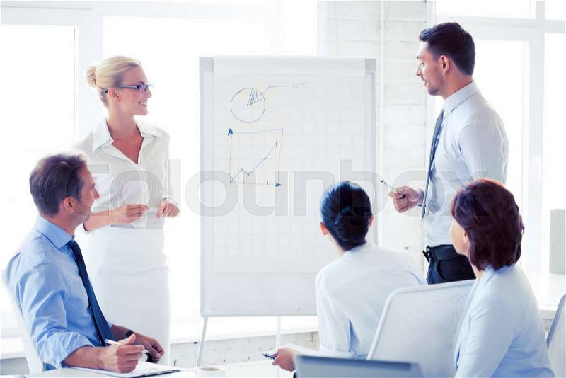 Smiling business team working with flip chart in office, stock photo
