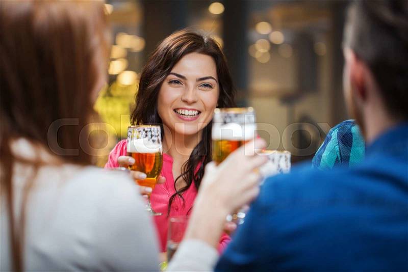 Leisure, eating, food and drinks, people and holidays concept - smiling friends having dinner and drinking beer at restaurant or pub, stock photo