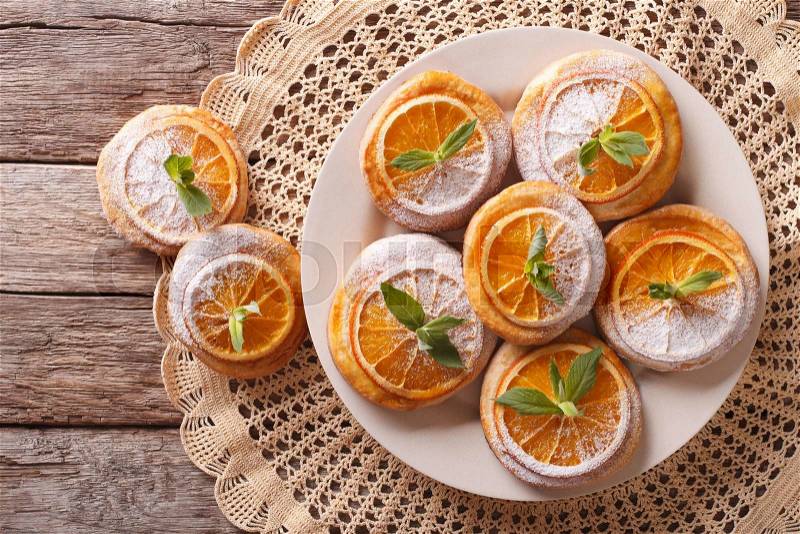 Tasty cookies with oranges, decorated with mint and powdered sugar close-up on a plate. Horizontal view from above , stock photo