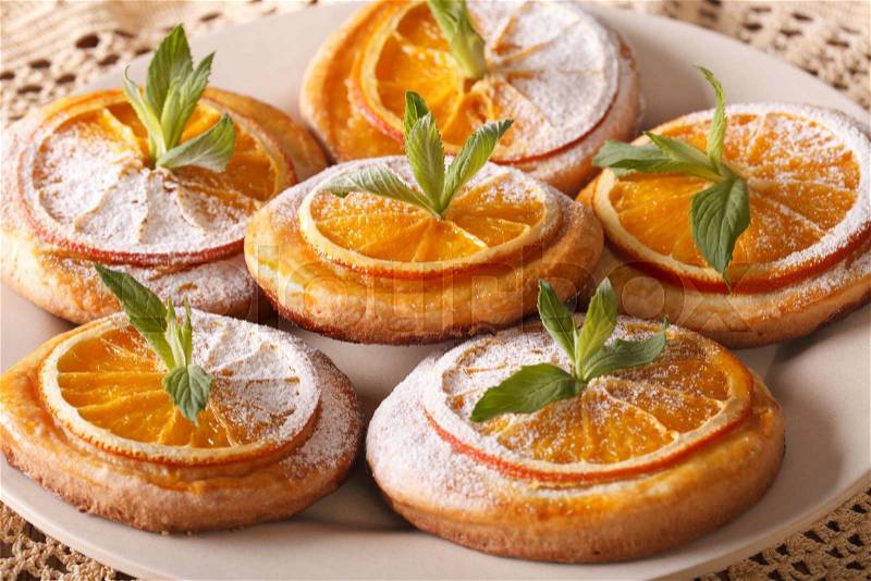 Tasty cookies with oranges, decorated with mint and powdered sugar close-up on a plate. horizontal , stock photo