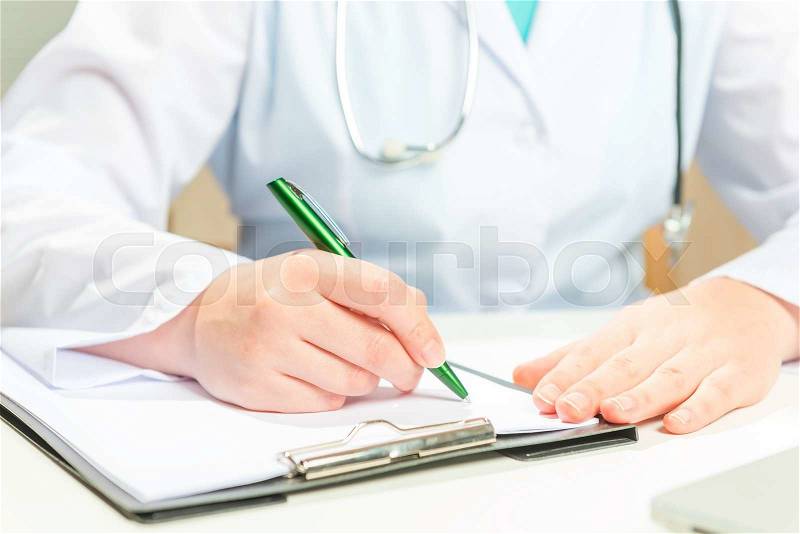 Doctor in a white coat writes on a paper prescription , stock photo