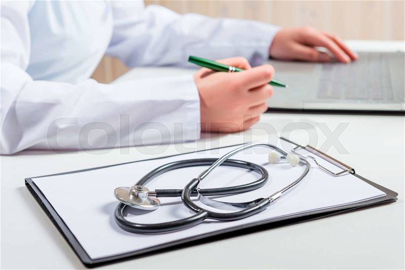 Stethoscope lies on a folder on the table and the doctor works, stock photo