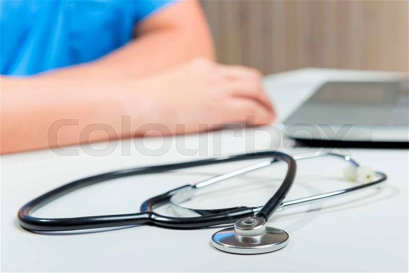 Stethoscope in focus, hands out of focus doctor close-up , stock photo