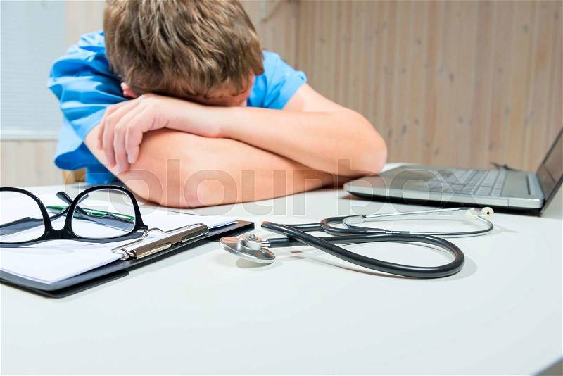 Tired Doctor sleeps at the table in working hours in the office, stock photo