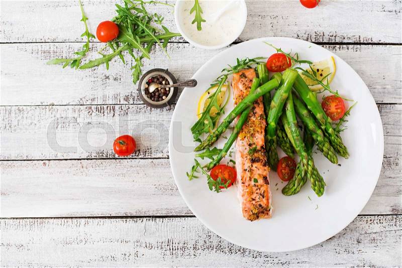 Baked salmon garnished with asparagus and tomatoes with herbs. Top view, stock photo