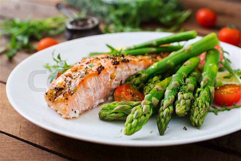 Baked salmon garnished with asparagus and tomatoes with herbs, stock photo