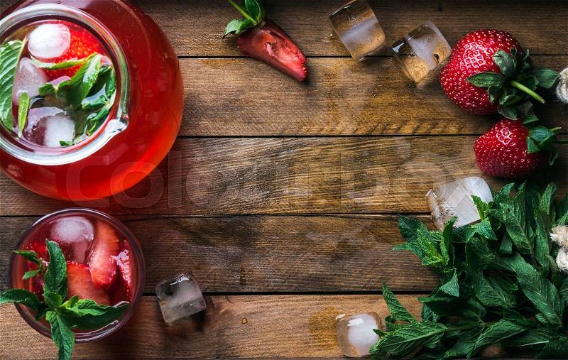 Homemade strawberry lemonade with mint and ice, served with fresh berries over wooden background, top view, copy space. Food frame , stock photo