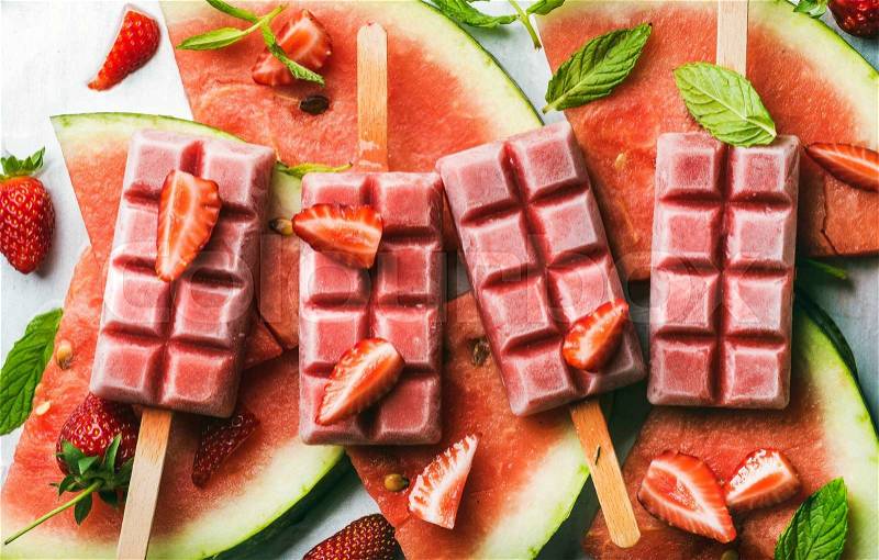 Strawberry watermelon ice cream popsicles with mint over steel tray background. Top view, horizontal, stock photo