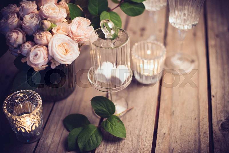 Elegant vintage wedding table decoration with roses and candles, warm night light filter, stock photo
