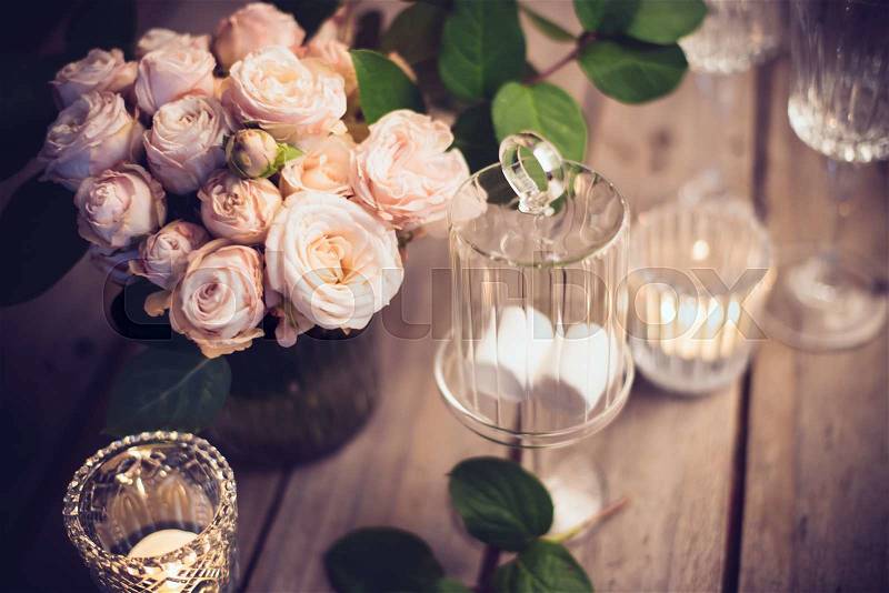 Elegant vintage wedding table decoration with roses and candles, warm night light filter, stock photo