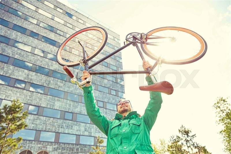 People, sport, style, leisure and lifestyle - happy young hipster man rising up and holding fixed gear bike s in city, stock photo