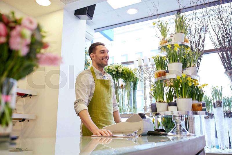 People, sale, retail, business and floristry concept - happy smiling florist man with cashbox standing at flower shop counter, stock photo