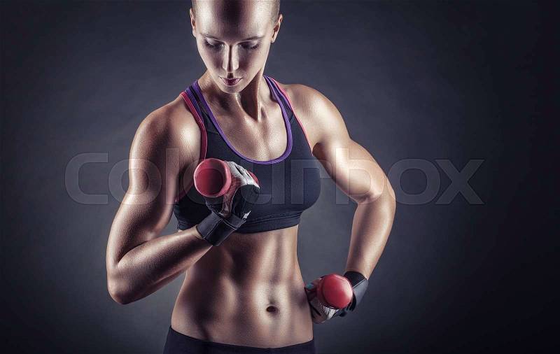 Fitness young woman with dumbbells on a dark background, stock photo