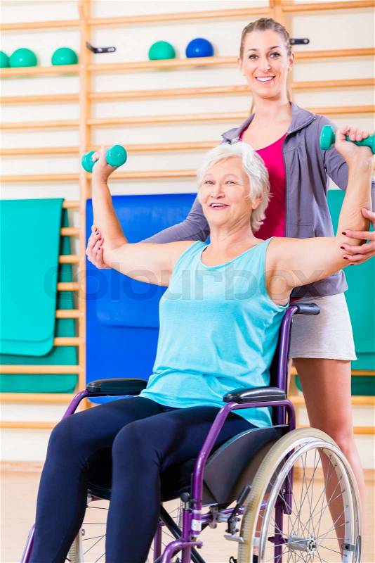 Senior woman in wheel chair doing physical therapy with her trainer, stock photo