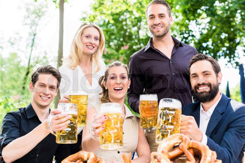 Friends or colleagues on beer garden after work toasting with drinks, stock photo