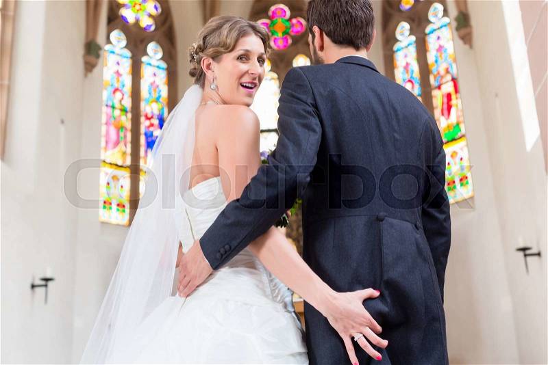 Bride grabbing ass of groom at wedding in church, stock photo