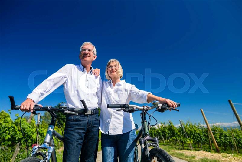 Senior couple enjoying view on bike trip, woman and man leaning against each other, stock photo