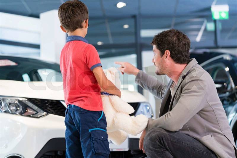 Father with son in car dealer showroom buying auto, stock photo