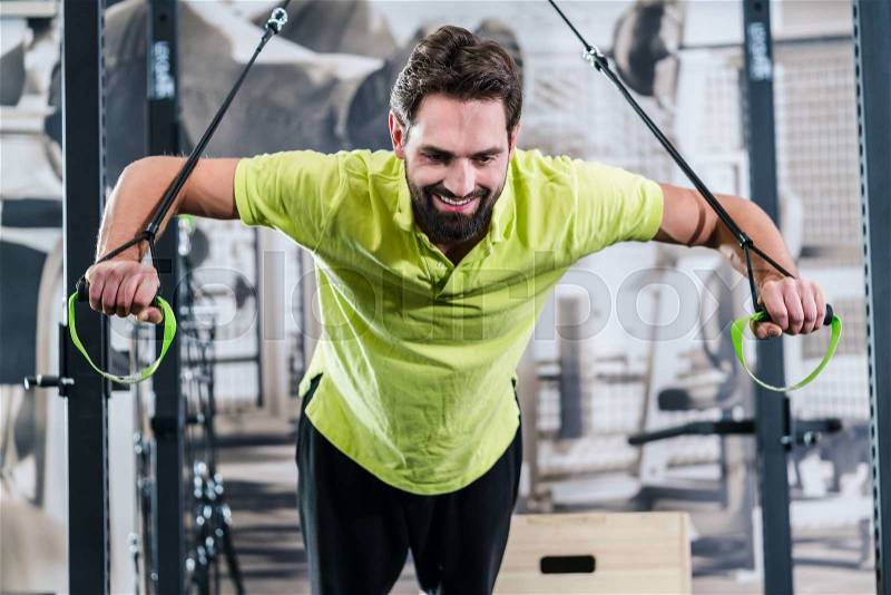 Man doing pushup with rings in functional training gym, stock photo